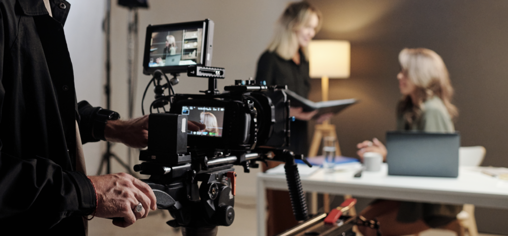 A man filming two women having a conversation in the office 